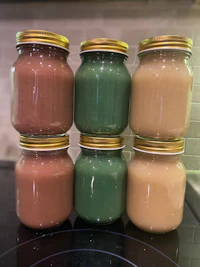 five jars of different colored liquids sitting on top of a stove