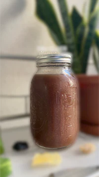 a jar of chocolate sauce on a counter next to a plant