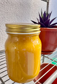 a jar of honey sitting on a shelf next to a plant