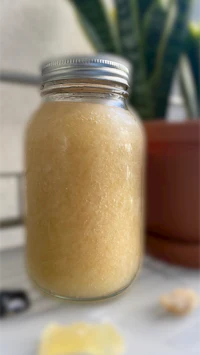 a jar of honey in a glass next to a plant